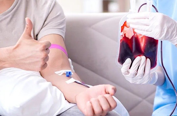 Seorang pria sedang melakukan proses donor darah dengan didampingi tenaga medis.